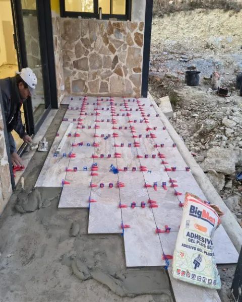 Operario extendiendo cemento cola y colocando el gres del porche