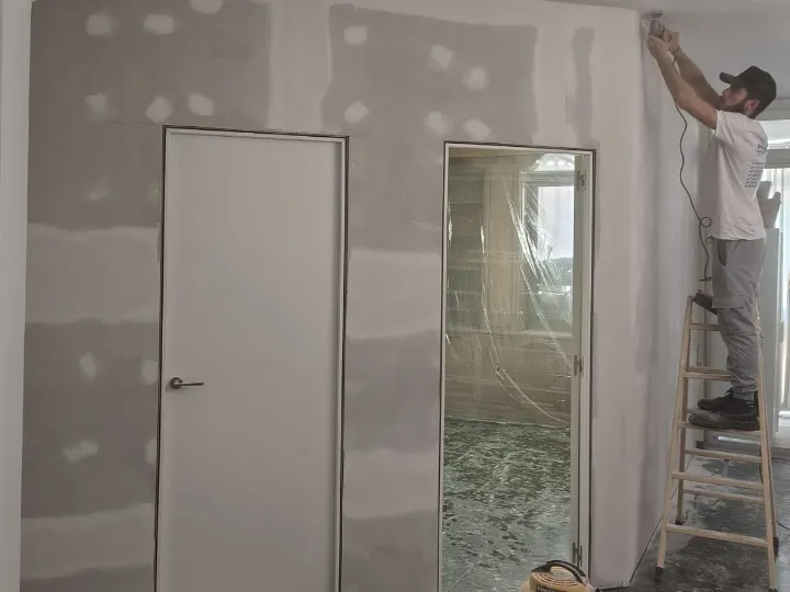 Operario lijando el encuentro de un tabique antes de pintar